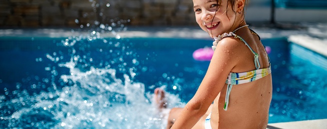 Child splashing in a backyard swimming pool